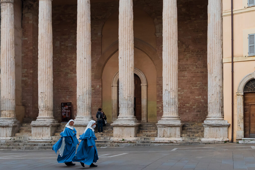 Nuns walkign past the temple of Minerva in Assisi